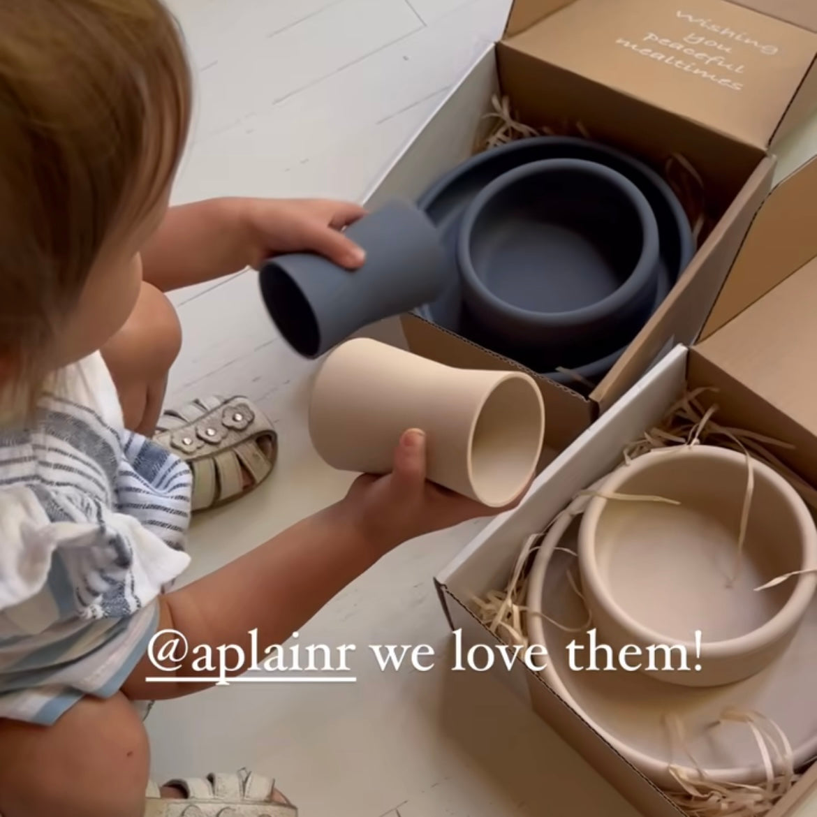 toddler checking out beige and blue cups from Aplainr mealtime set